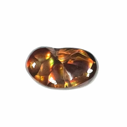 A loose Mexican fire agate gemstone.  The stone is red with a puddle of purple and exhibits a metallic luster.