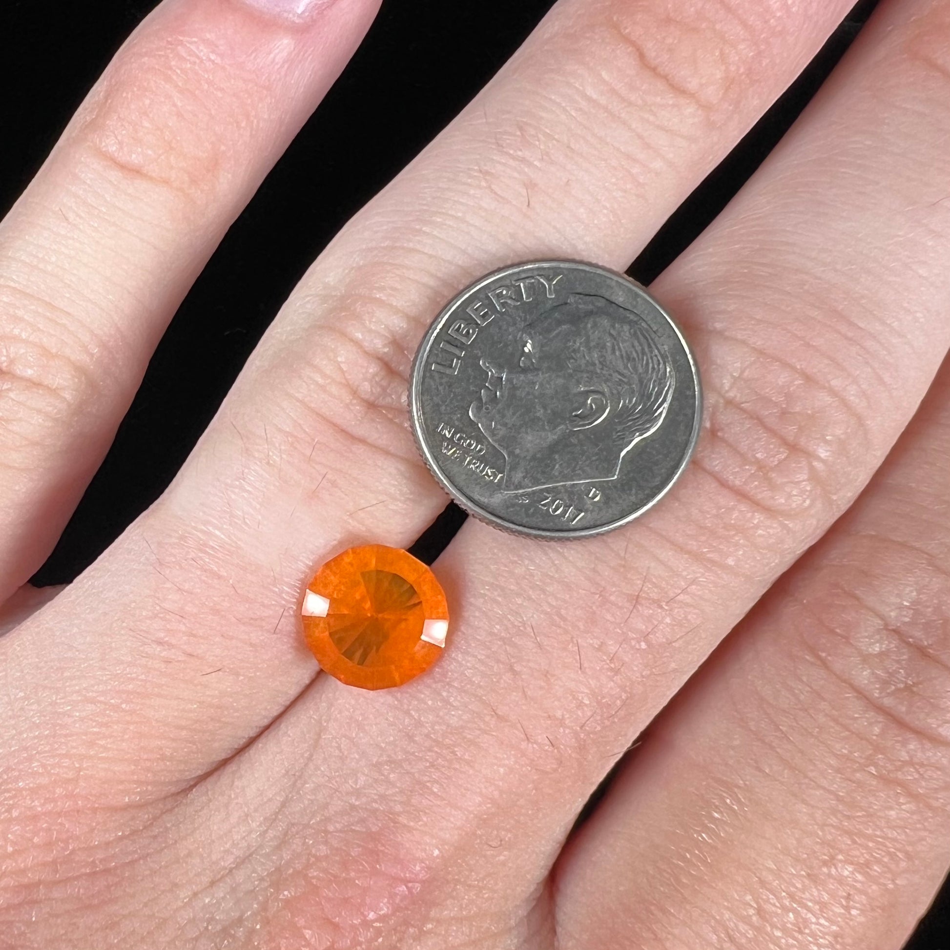 A loose, round faceted cut fire opal from Mexico.  The body color is yellowish orange with red, green, and yellow fire.