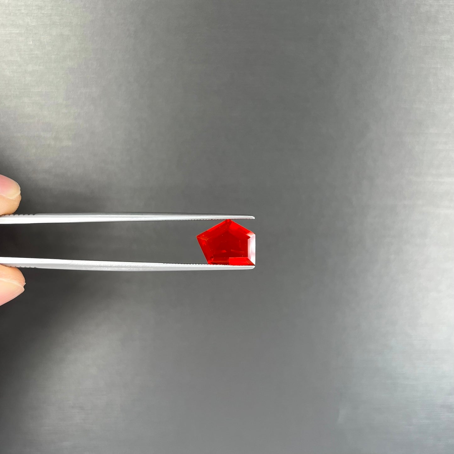 A loose, faceted freeform cut Mexican fire opal gemstone.  The stone is a cherry red color.