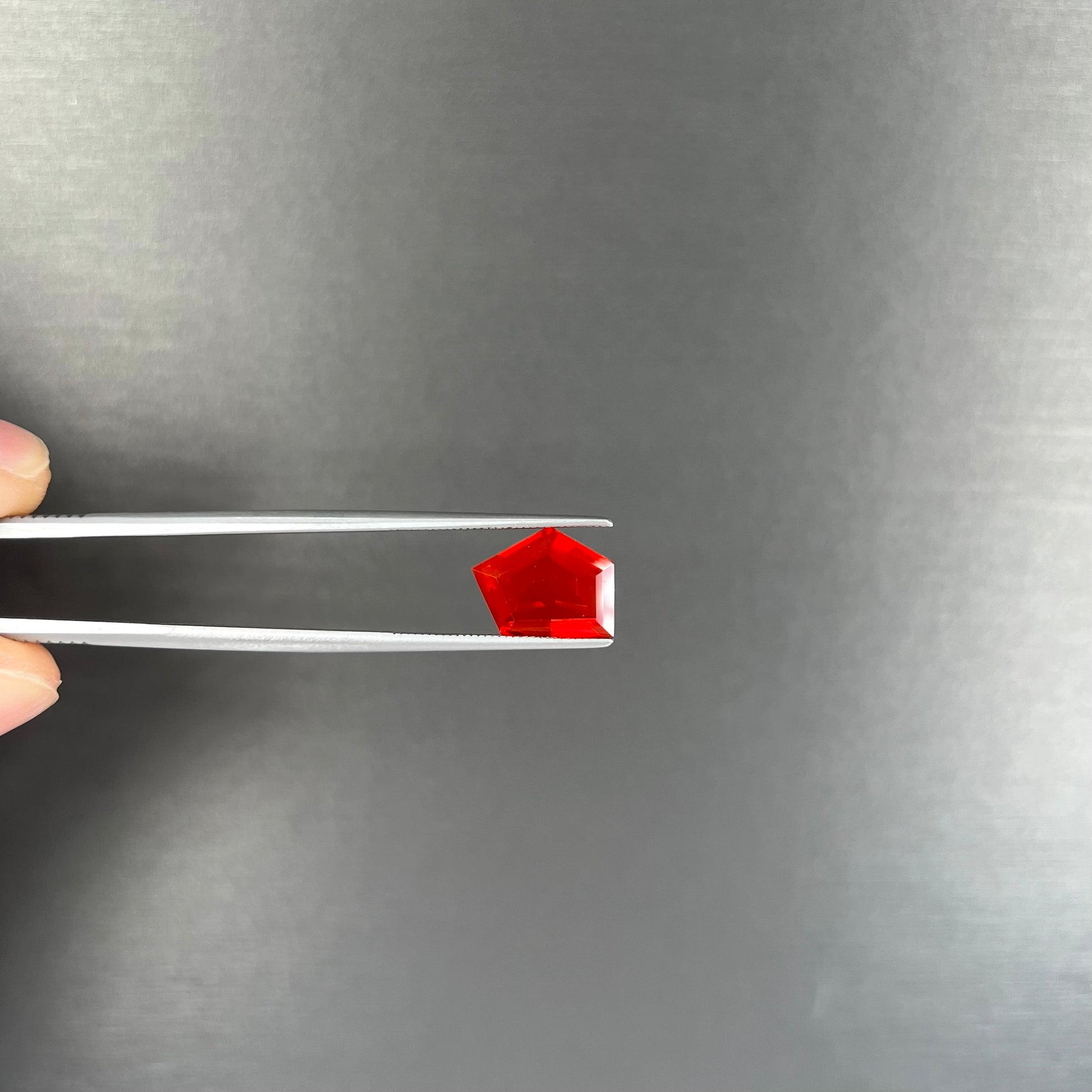 A loose, faceted freeform cut Mexican fire opal gemstone.  The stone is a cherry red color.