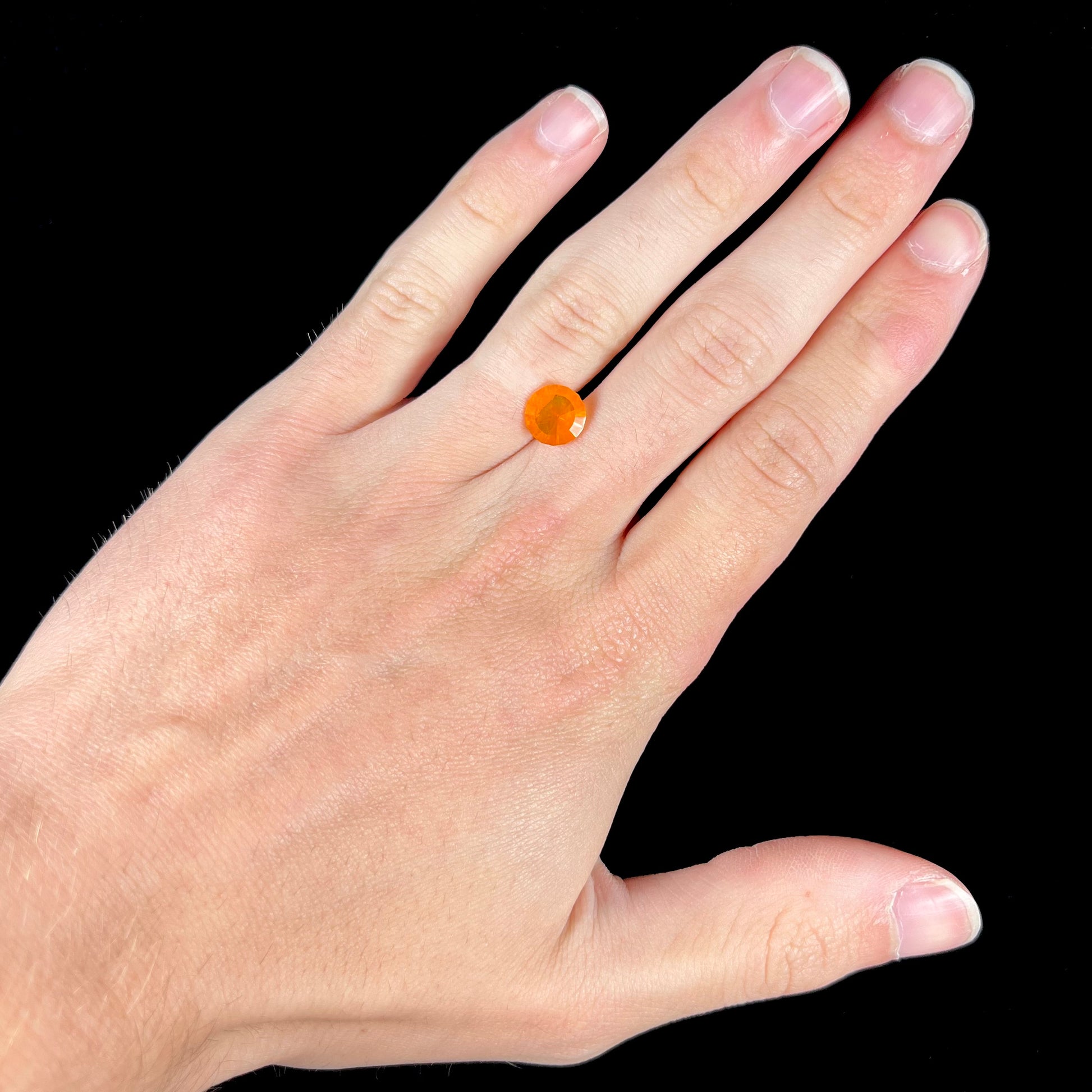 A loose, round faceted cut fire opal from Mexico.  The body color is yellowish orange with red, green, and yellow fire.