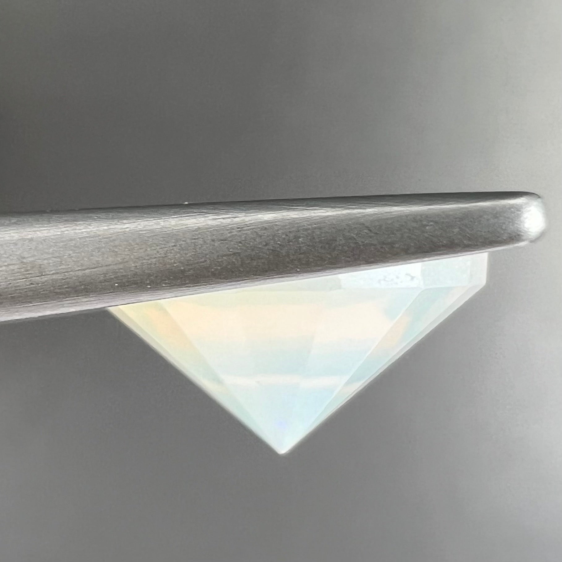 A loose, modified round cut Mexican fire opal gemstone.  The stone is transluscent light yellow with green and blue fire.
