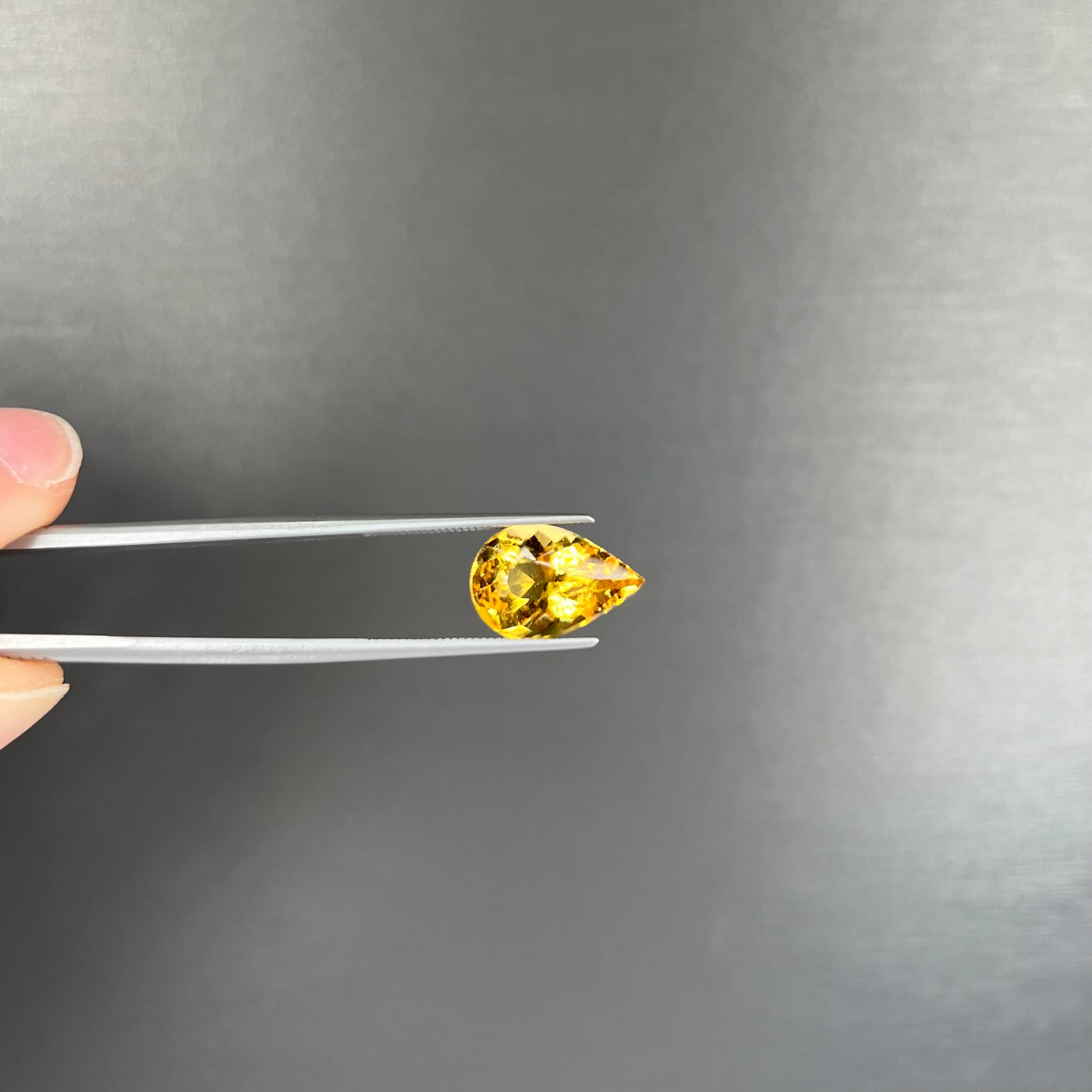 A loose, pear shaped golden beryl gemstone.