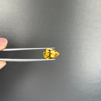 A loose, pear shaped golden beryl gemstone.
