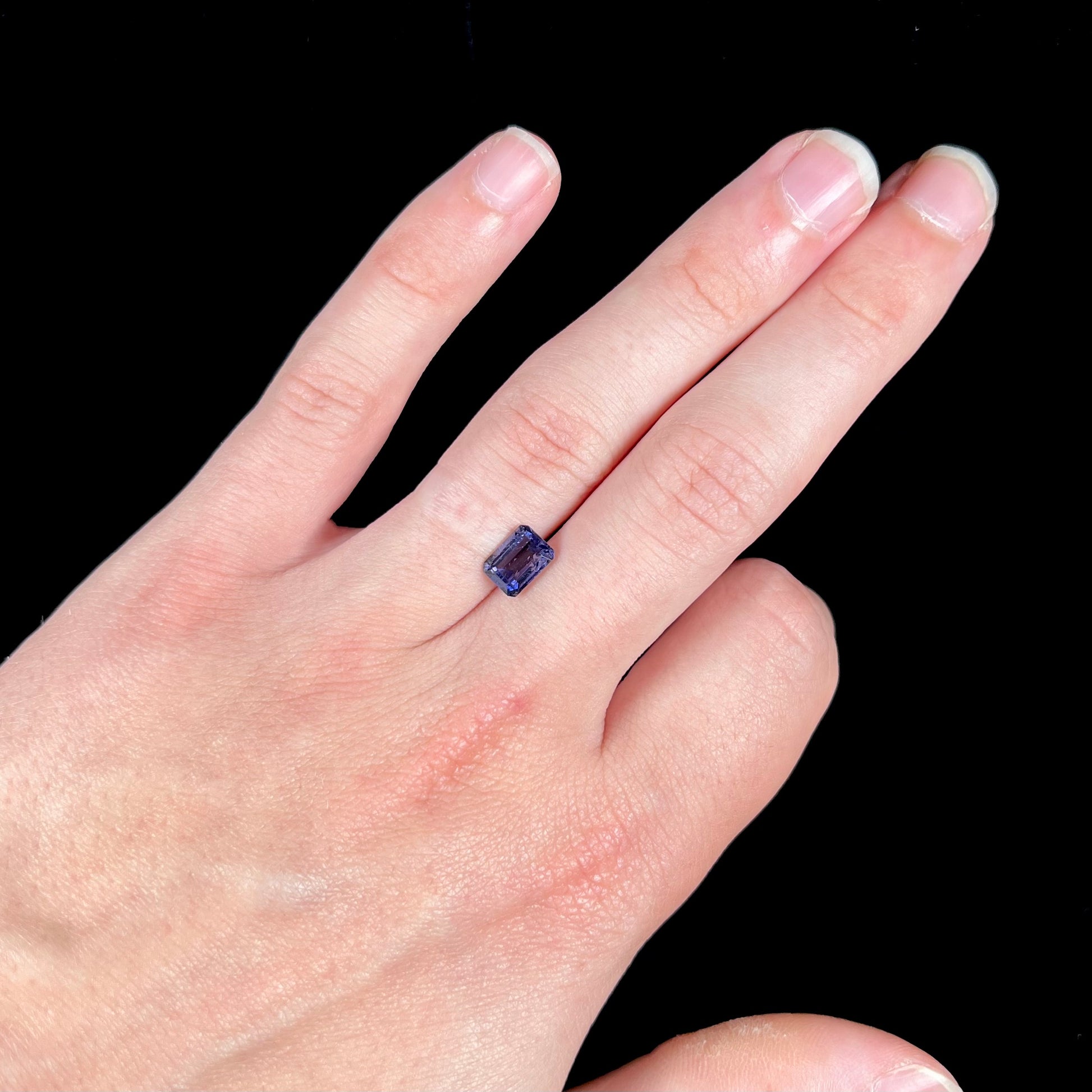 A loose, emerald cut blue iolite gemstone.