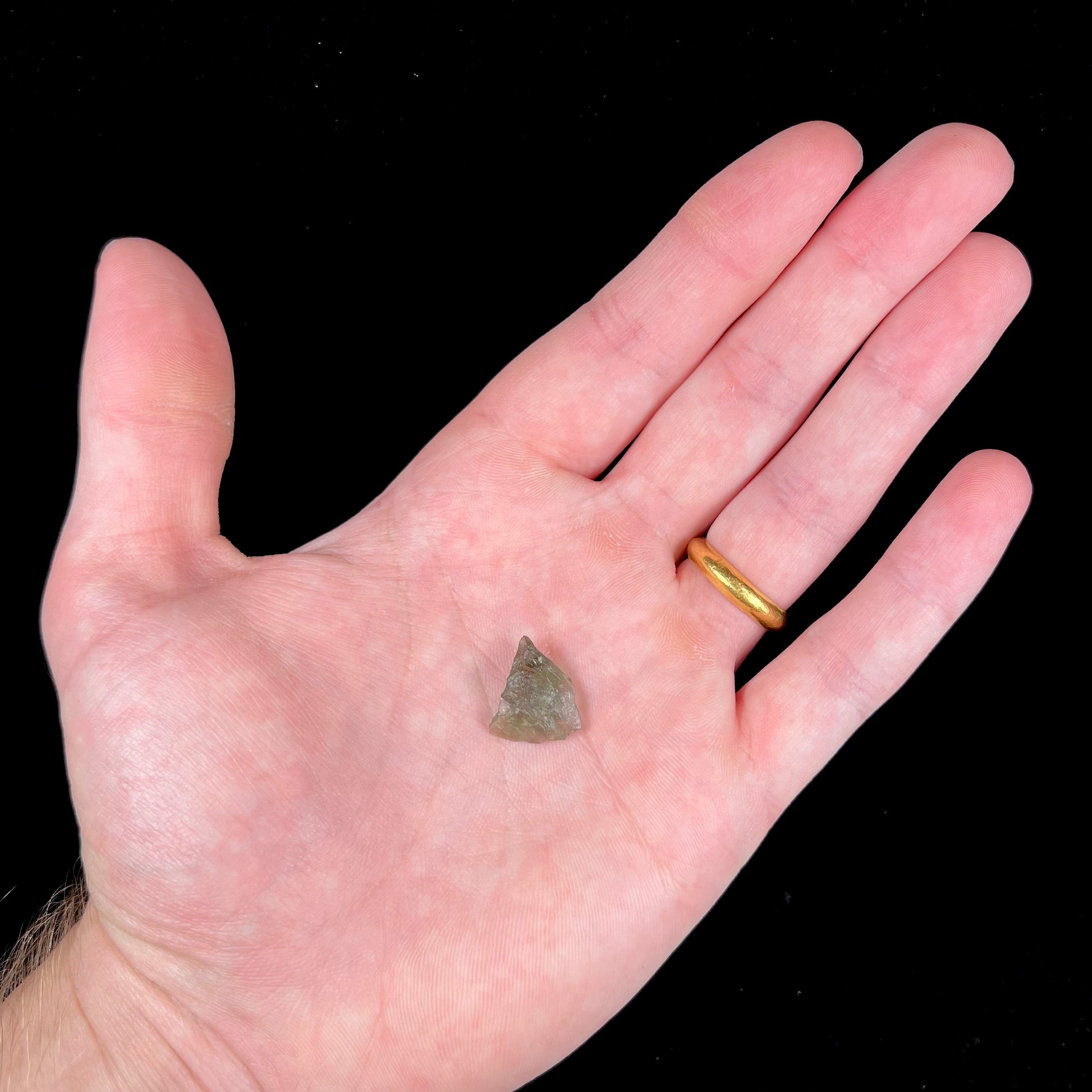 A natural, rough moldavite crystal.  The stone is green color and transluscent.