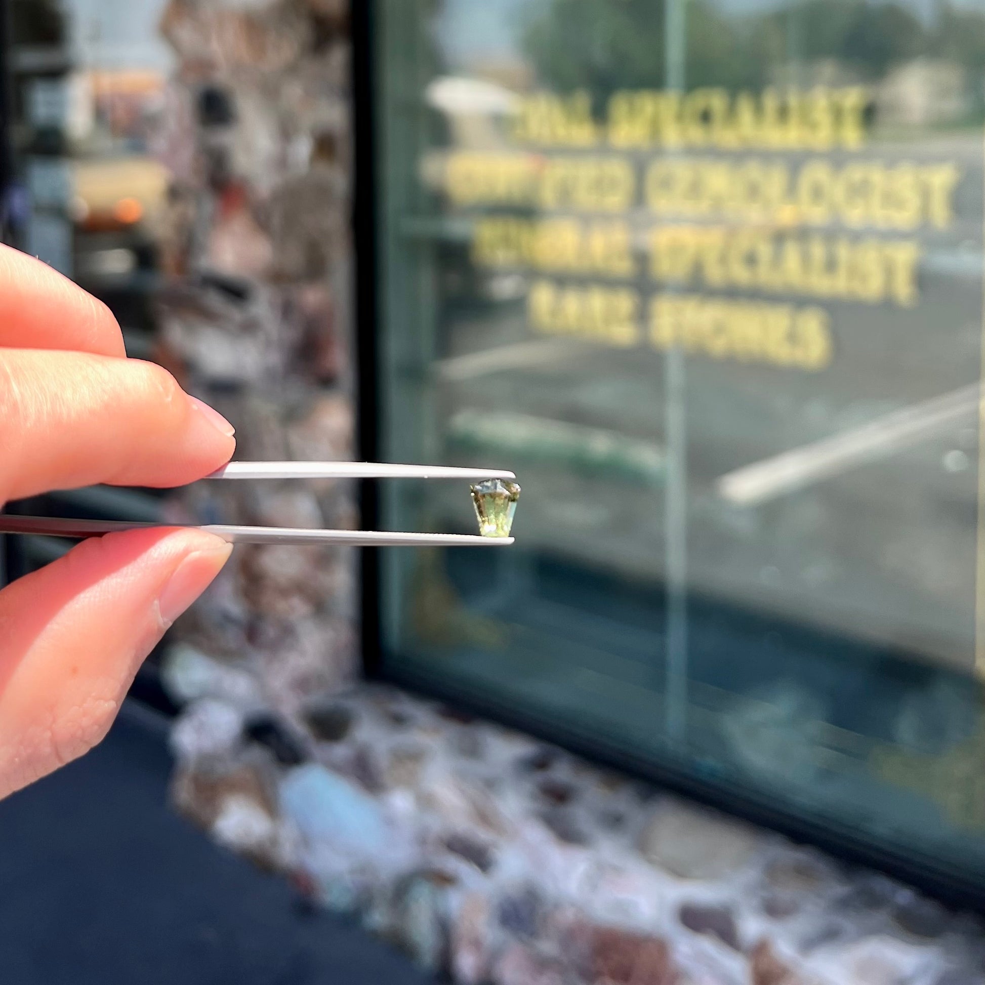 A loose, shield cut, natural moldavite gemstone.  The stone has a small chip in the top corner facet.