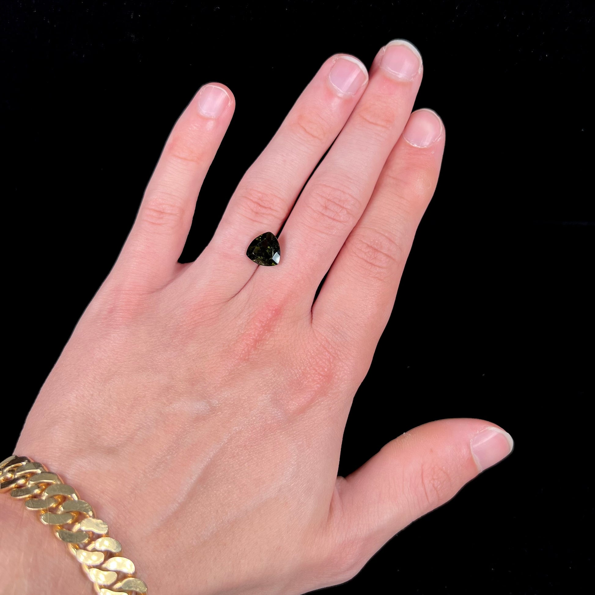 A natural, trillion cut moldavite gemstone.
