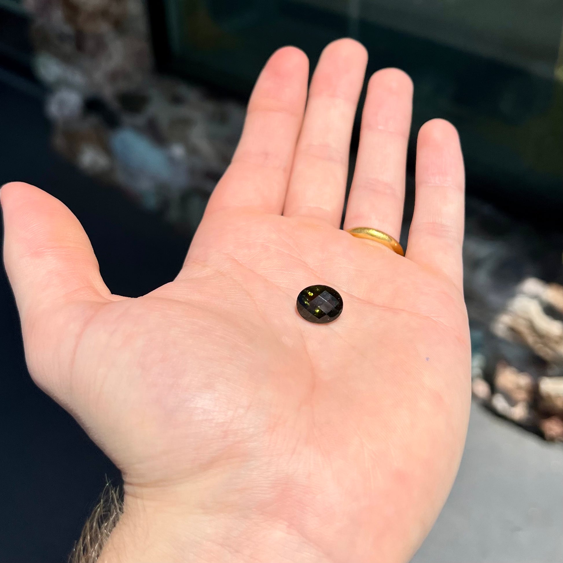 A loose, faceted oval cut natural moldavite gemstone.