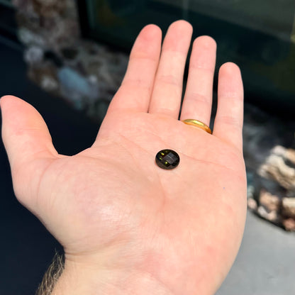 A loose, faceted oval cut natural moldavite gemstone.