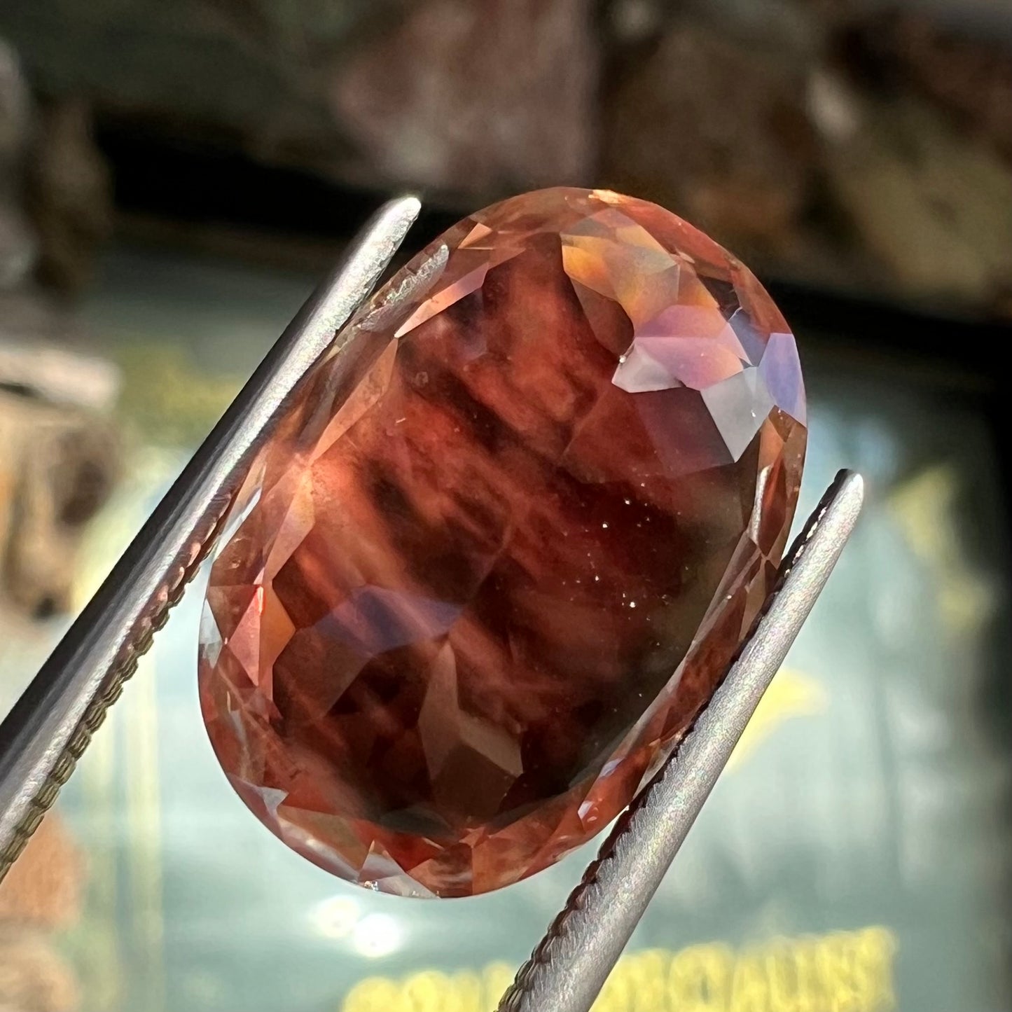 A faceted, oval cut sunstone.  The stone is red-orange color with a bright schiller flash.