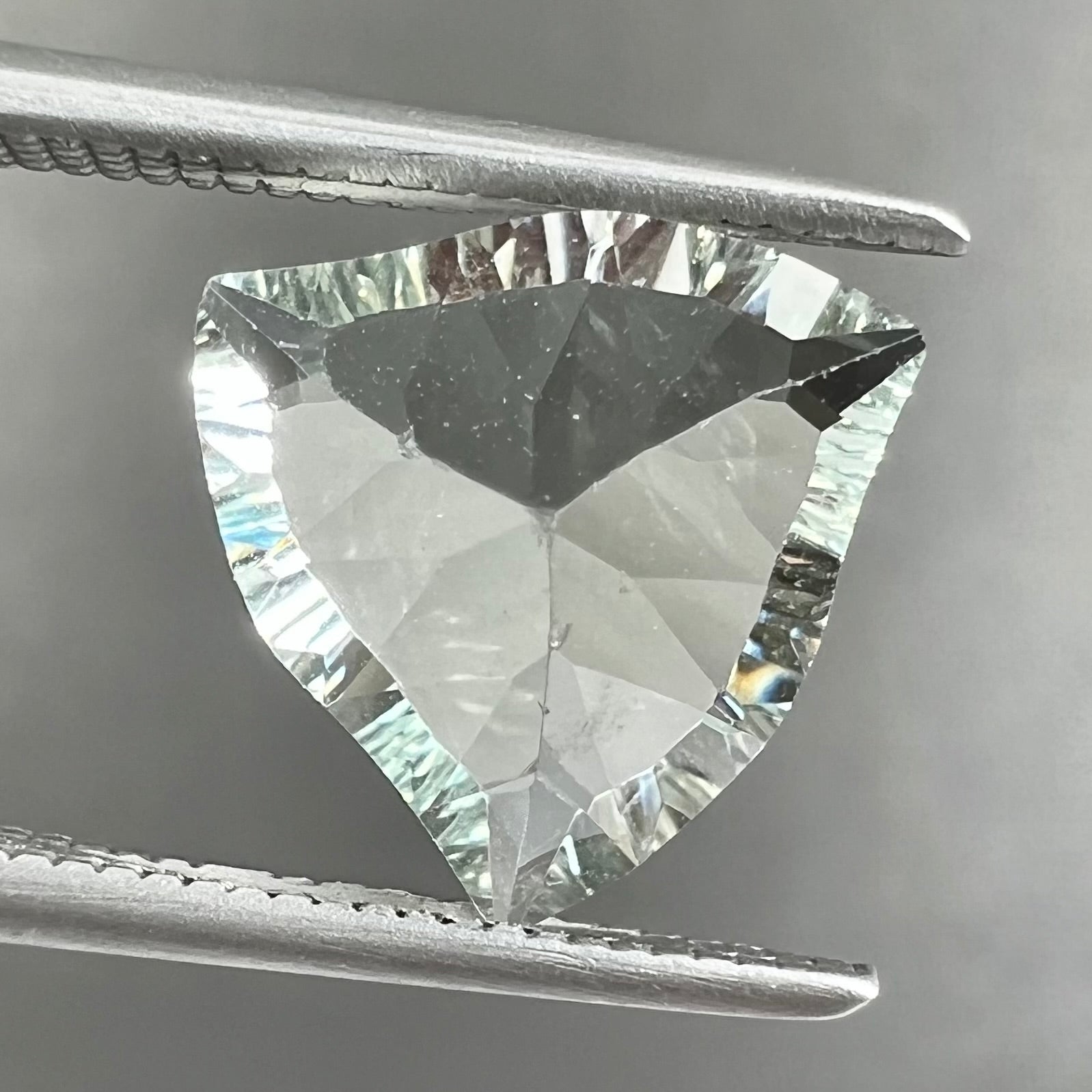A loose, triangular fantasy cut prasiolite gemstone.  Prasiolite is a light green variety of quartz.