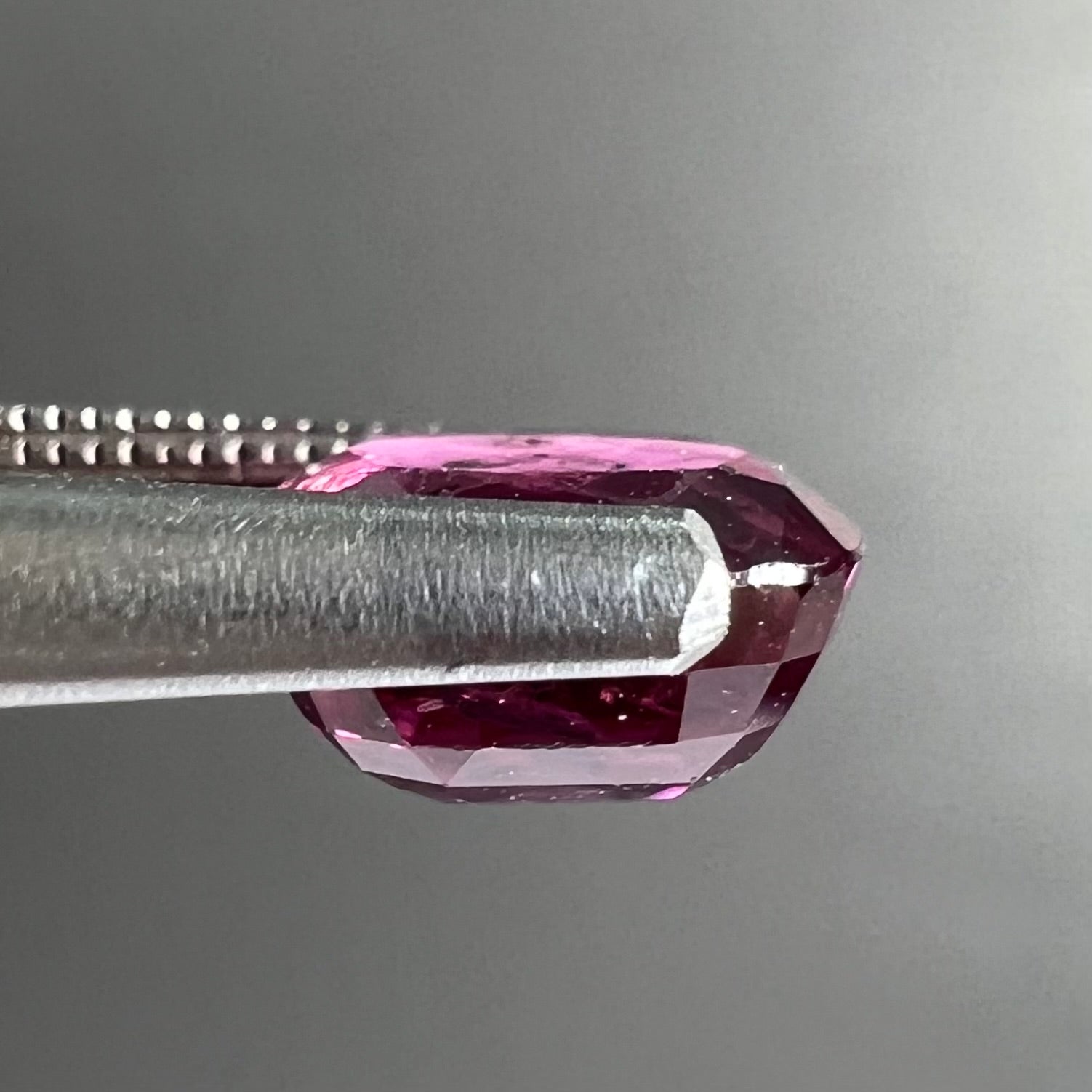 A loose, faceted oval cut natural purple sapphire.  The stone has a burst crystal inclusion.