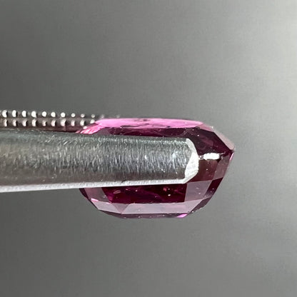 A loose, faceted oval cut natural purple sapphire.  The stone has a burst crystal inclusion.