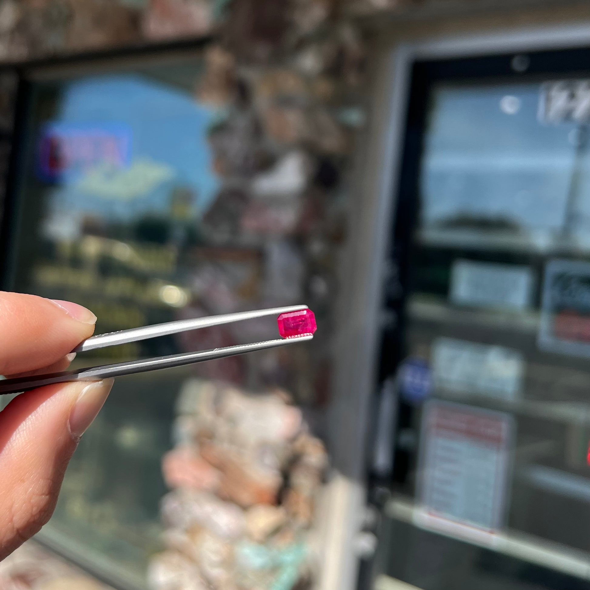 An emerald cut Burma ruby gemstone.  The stone is loose and a pinkish red color.