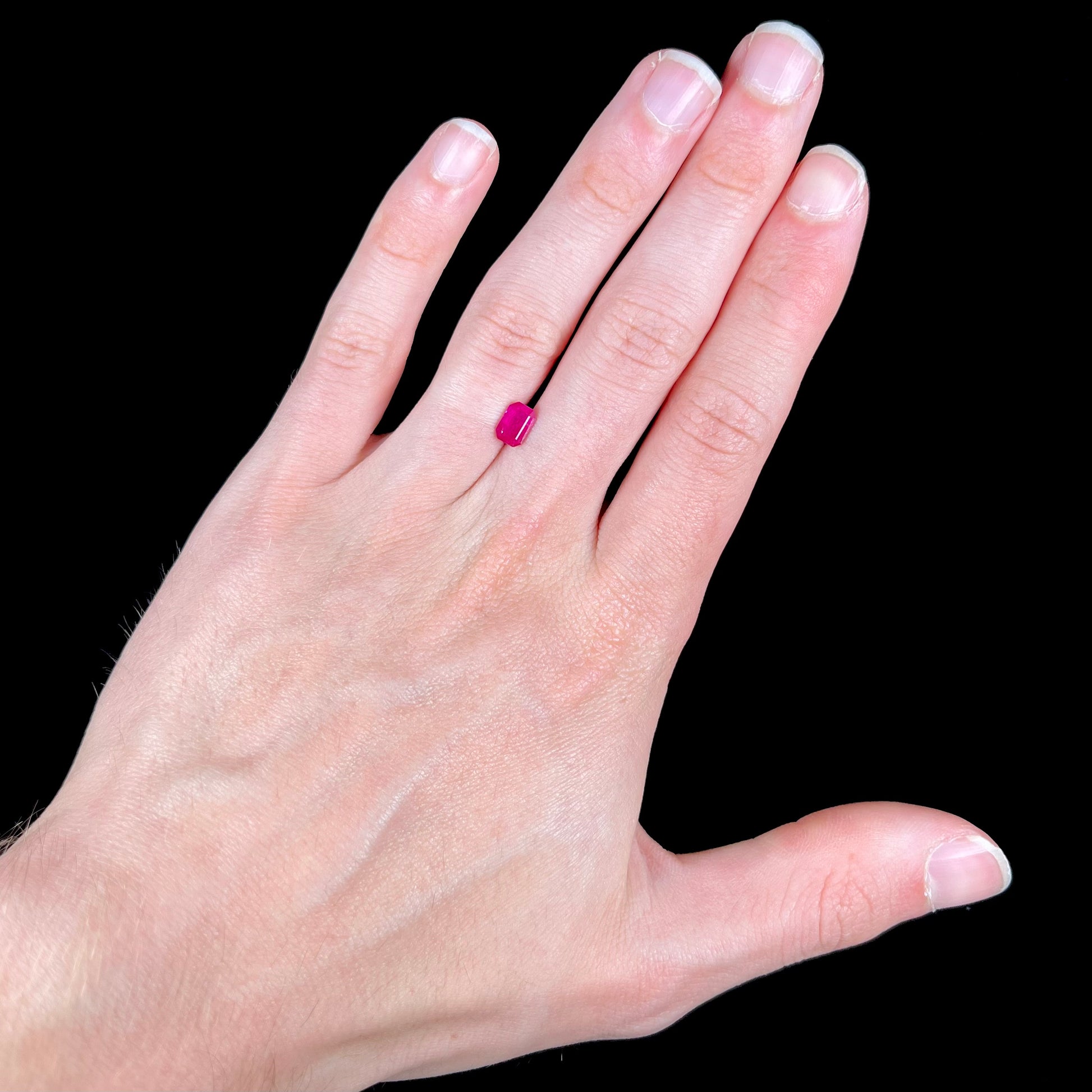 A natural, emerald cut Burma ruby with a purplish pinkish red color.