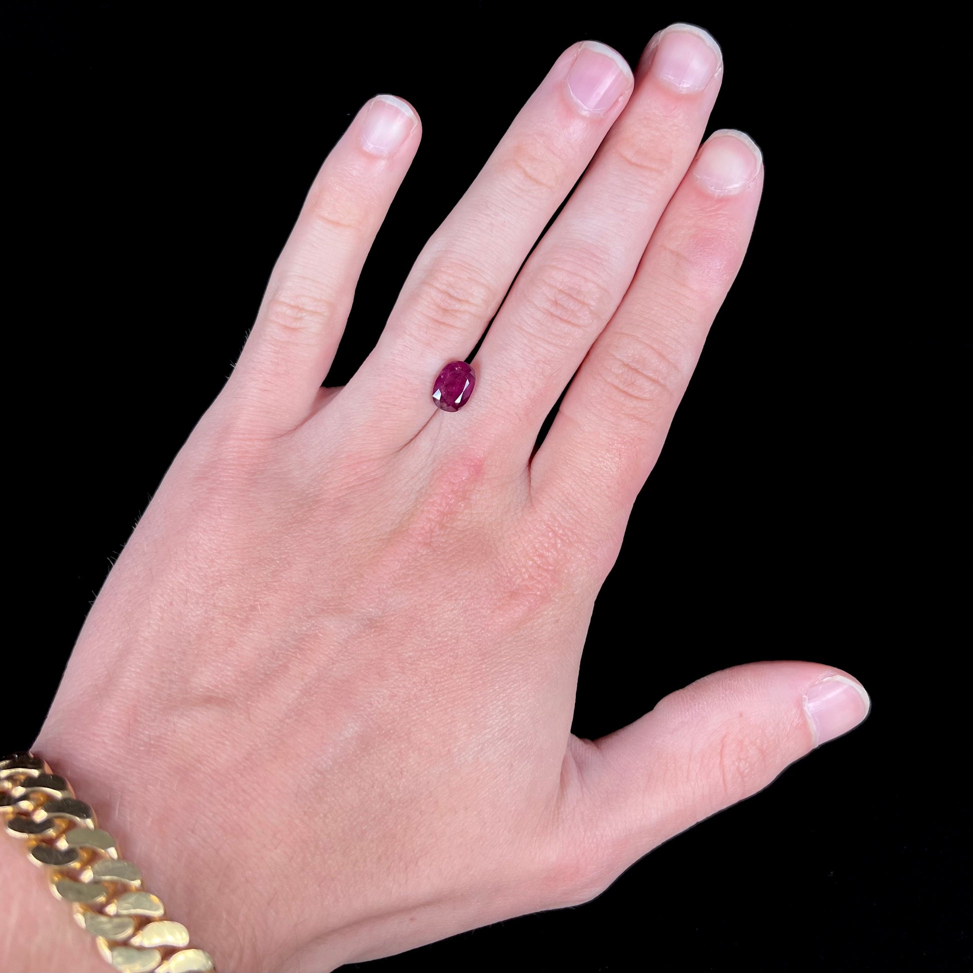A loose, natural purplish ruby gemstone.  There is a small, minute chip on the girdle of the gem.