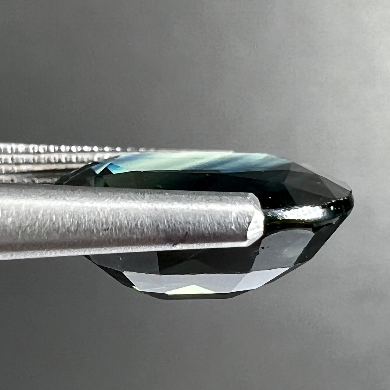A loose faceted oval cut natural sapphire.  The stone is blue-green color.