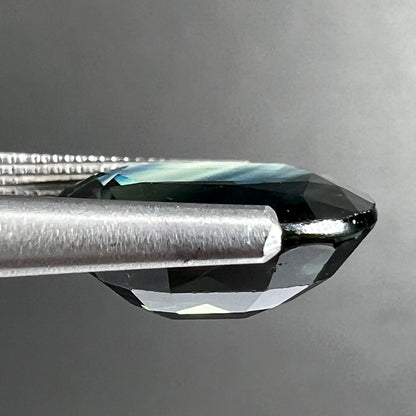A loose faceted oval cut natural sapphire.  The stone is blue-green color.