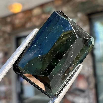 A faceted emerald cut dark green tourmaline gemstone.