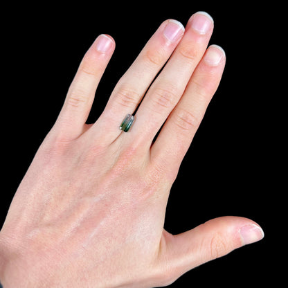 A loose, emerald cut tricolor tourmaline gemstone.  The stone transitions from green to blue to white colors.