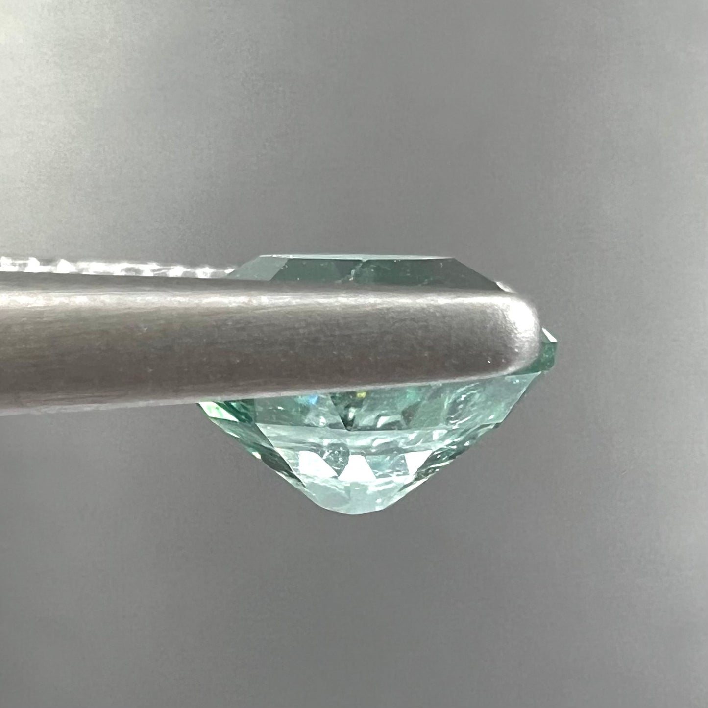 A loose, faceted modified oval cut mint green tourmaline gemstone.
