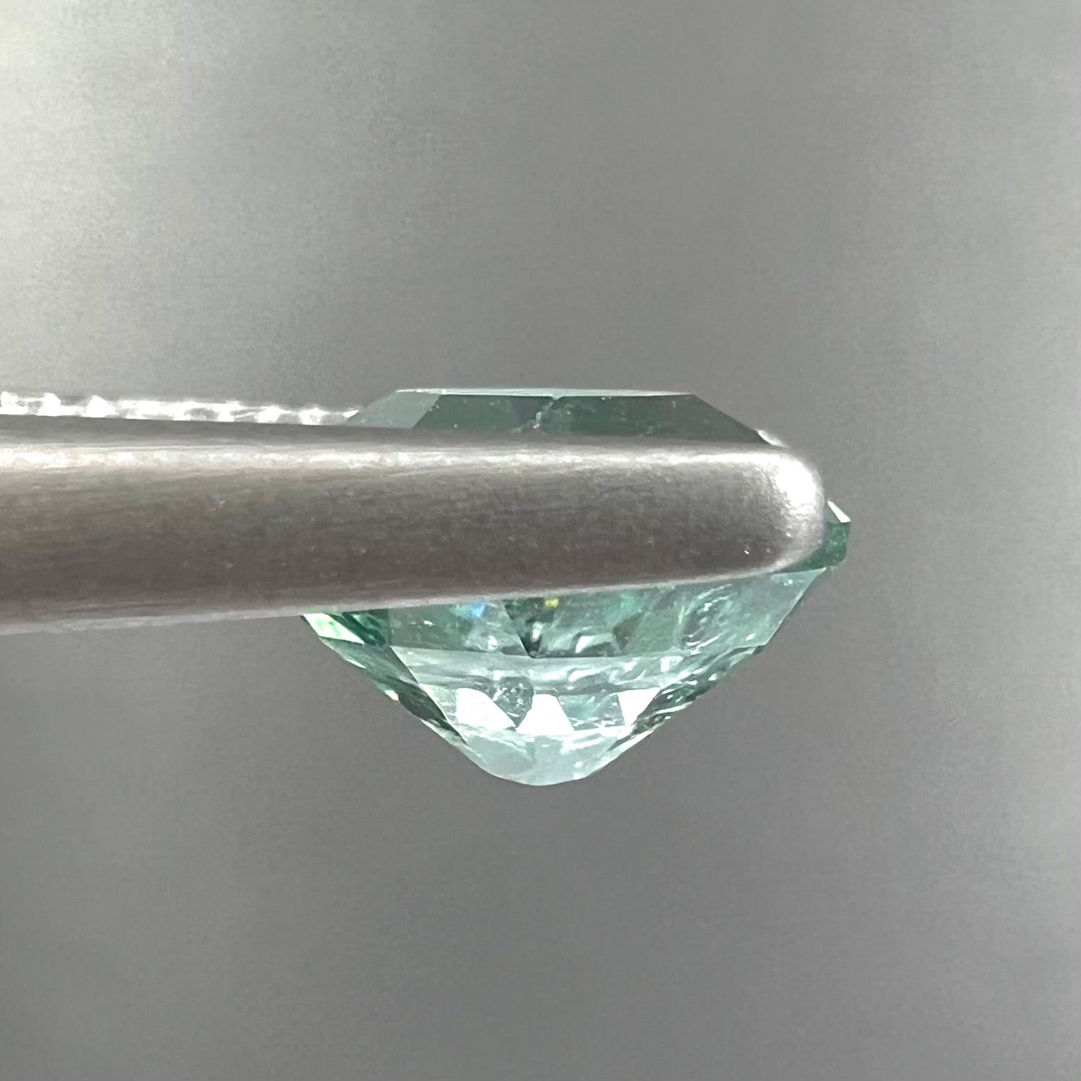 A loose, faceted modified oval cut mint green tourmaline gemstone.