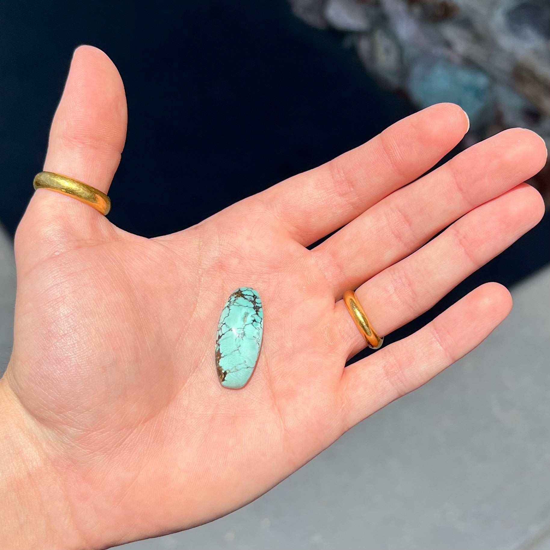 A loose, barrel cabochon cut Courtland-Gleeson turquoise stone.  The stone is greenish blue with black and brown matrix.
