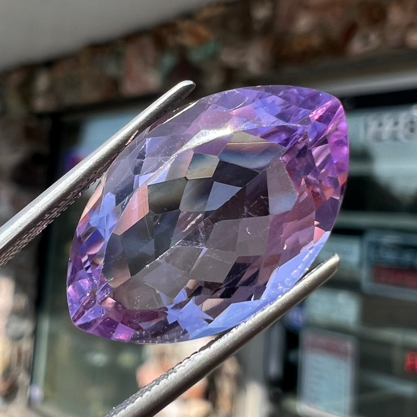 A loose marquise cut amethyst gemstone.  The stone is a light purple color and has scratches along the surface.