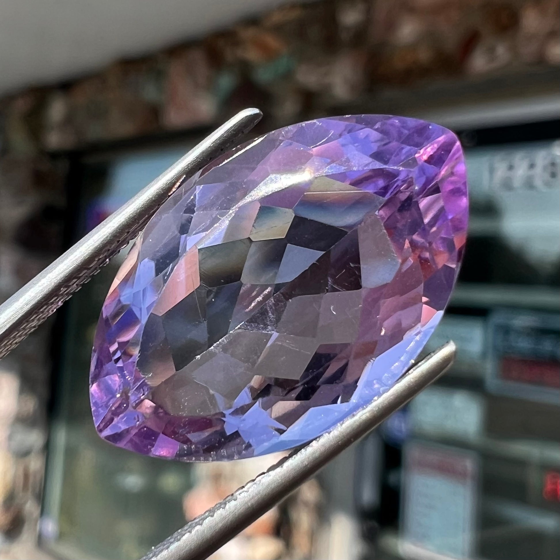 A loose marquise cut amethyst gemstone.  The stone is a light purple color and has scratches along the surface.