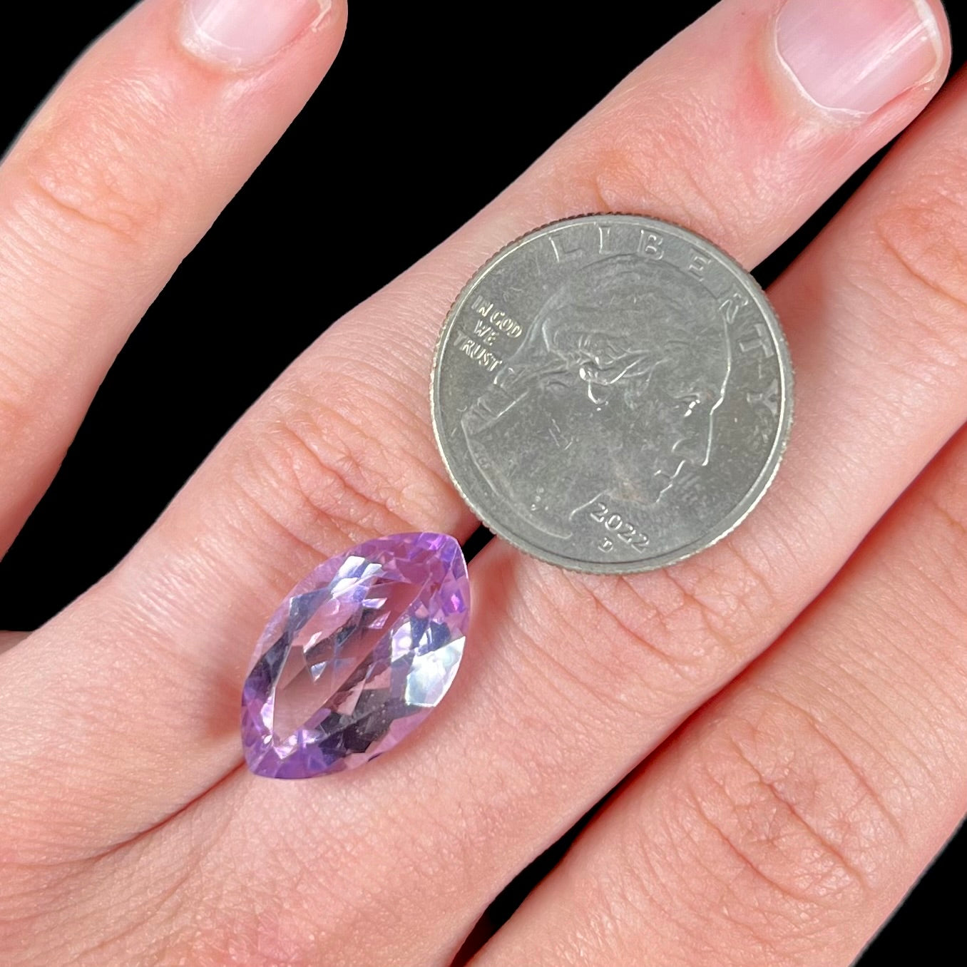 A loose marquise cut amethyst gemstone.  The stone is a light purple color and has scratches along the surface.