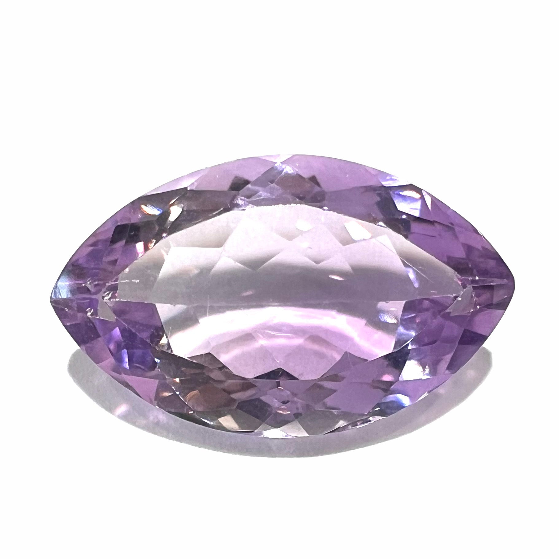 A loose marquise cut amethyst gemstone.  The stone is a light purple color and has scratches along the surface.