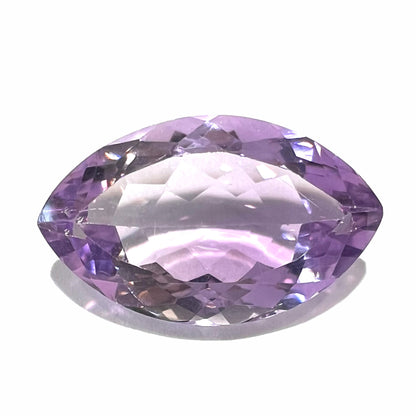 A loose marquise cut amethyst gemstone.  The stone is a light purple color and has scratches along the surface.