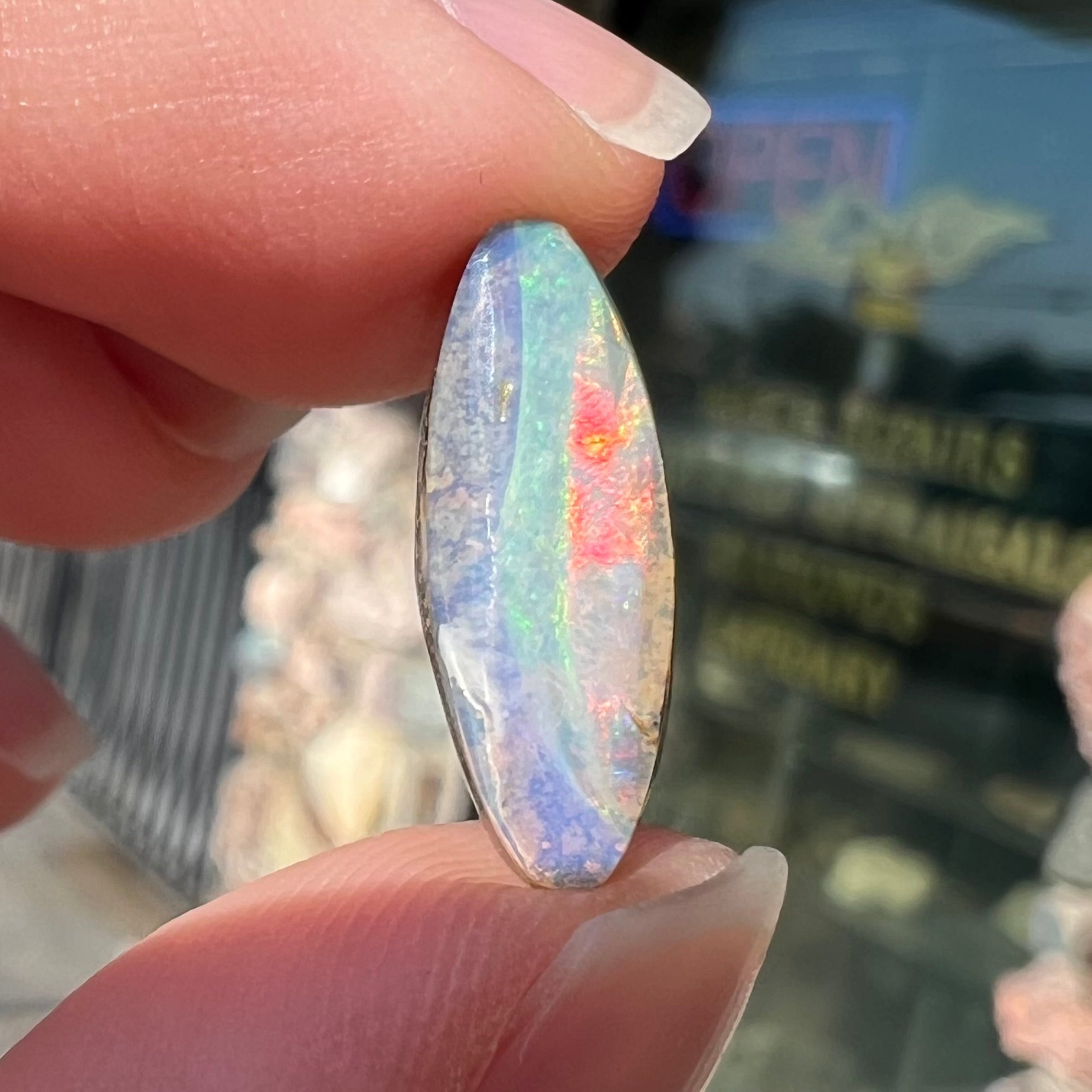A loose, marquise cut boulder opal from Quilpie, Australia.  The opal has green and red wave patterns.