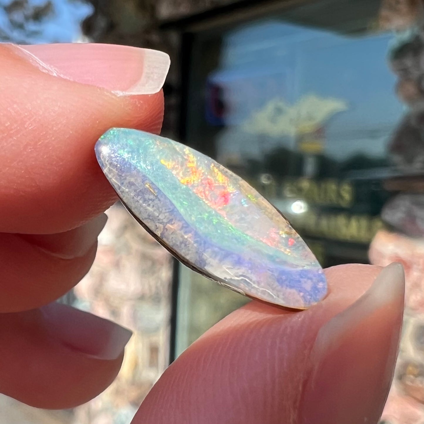 A loose, marquise cut boulder opal from Quilpie, Australia.  The opal has green and red wave patterns.