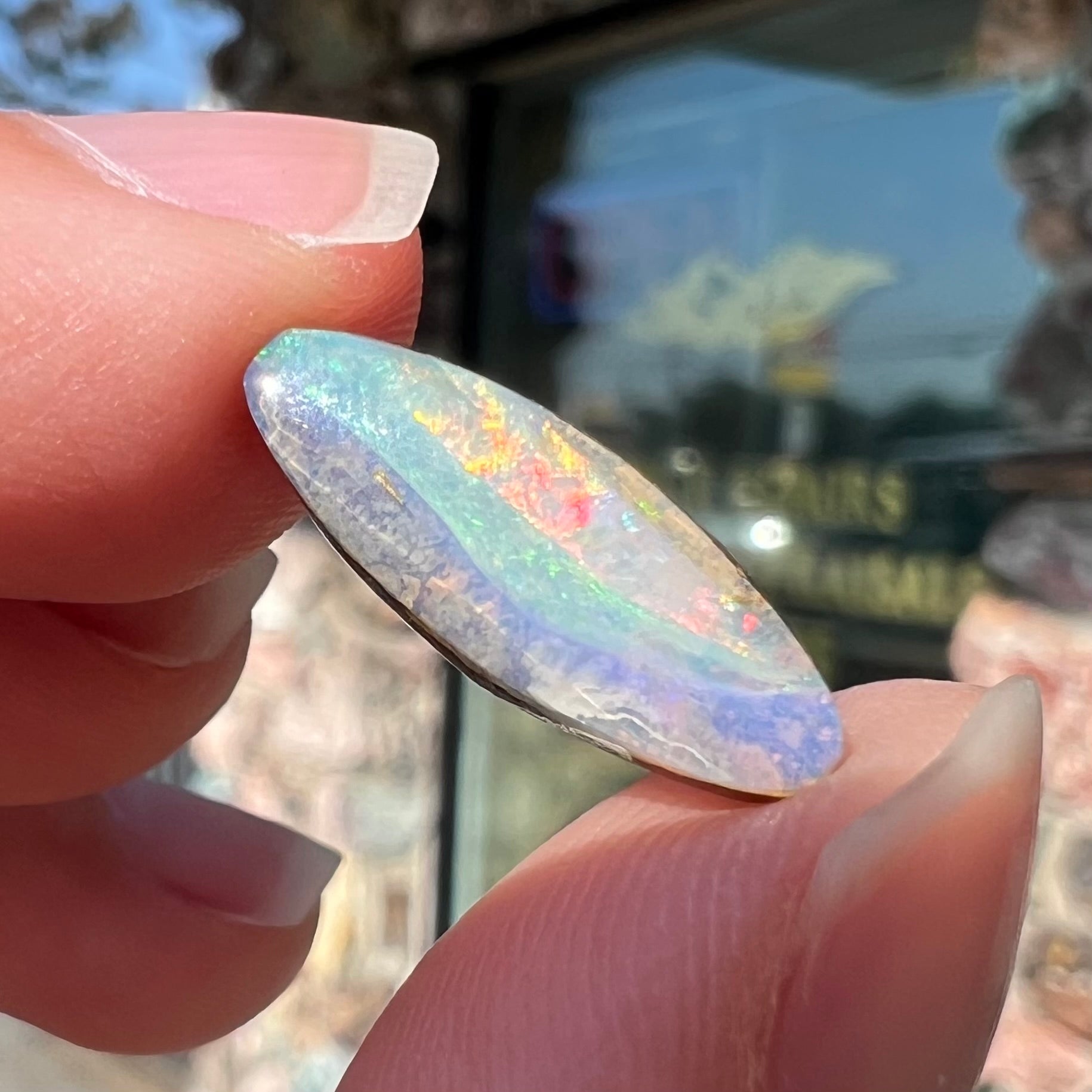 A loose, marquise cut boulder opal from Quilpie, Australia.  The opal has green and red wave patterns.