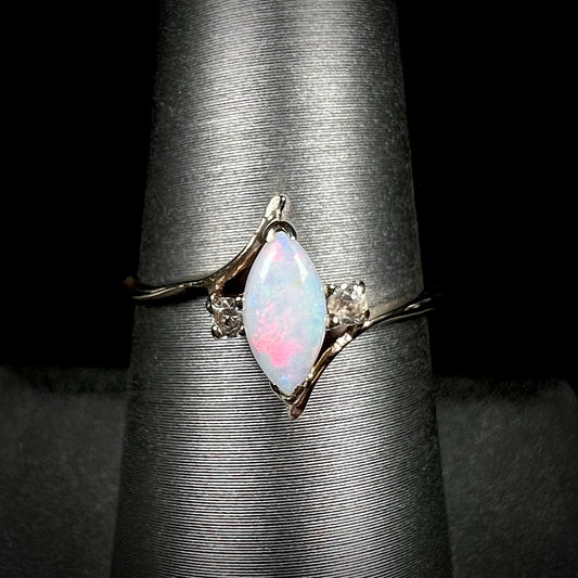 A yellow gold marquise cut opal ring set with two white sapphire accent stones.