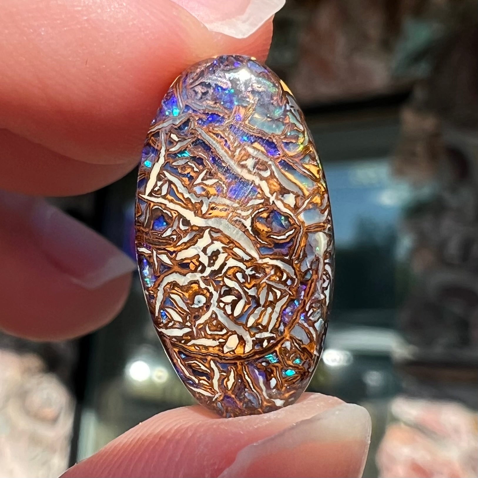 An oval cabochon cut Koroit boulder matrix opal stone.  The opal has blue colors.