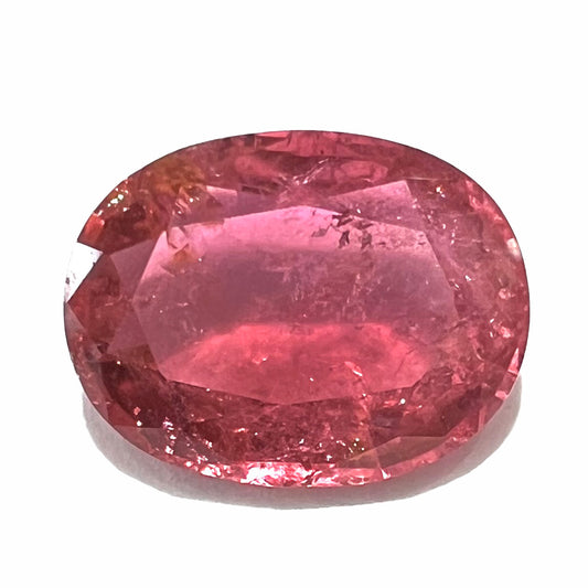 A faceted, oval cut, melon pink tourmaline gemstone.