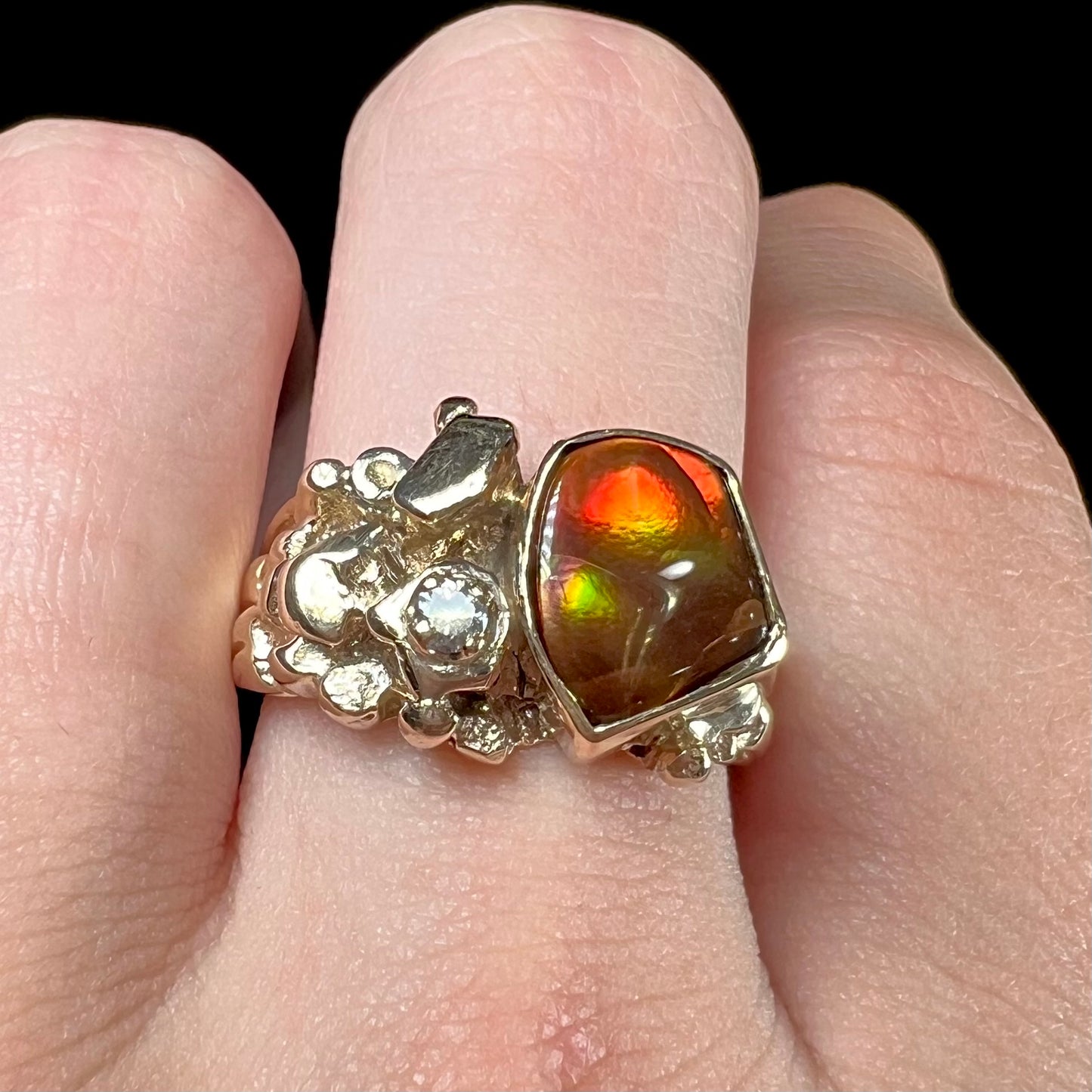 A men's yellow gold, nugget style ring set with a Mexican fire agate stone and a diamond accent.