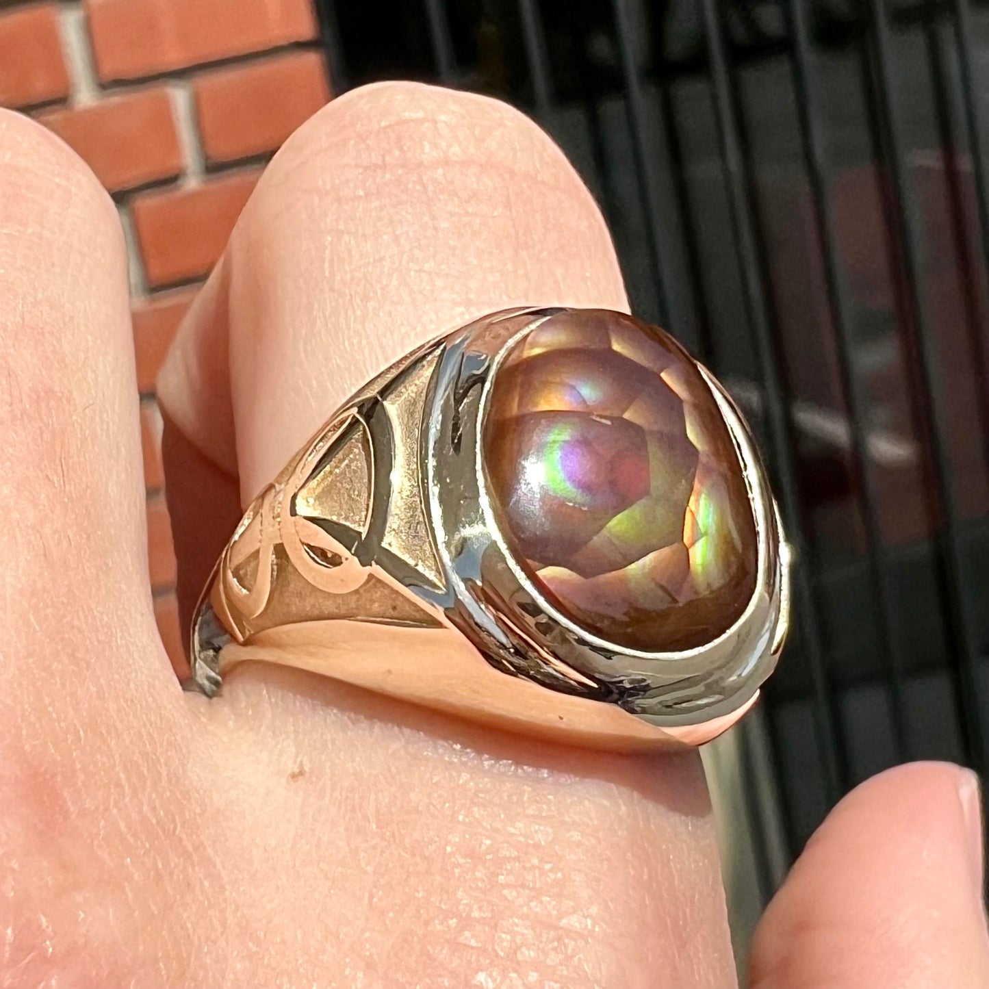 A men's solid yellow gold ring set with a Mexican fire agate stone.  The fire agate has a puple bull's eye pattern.