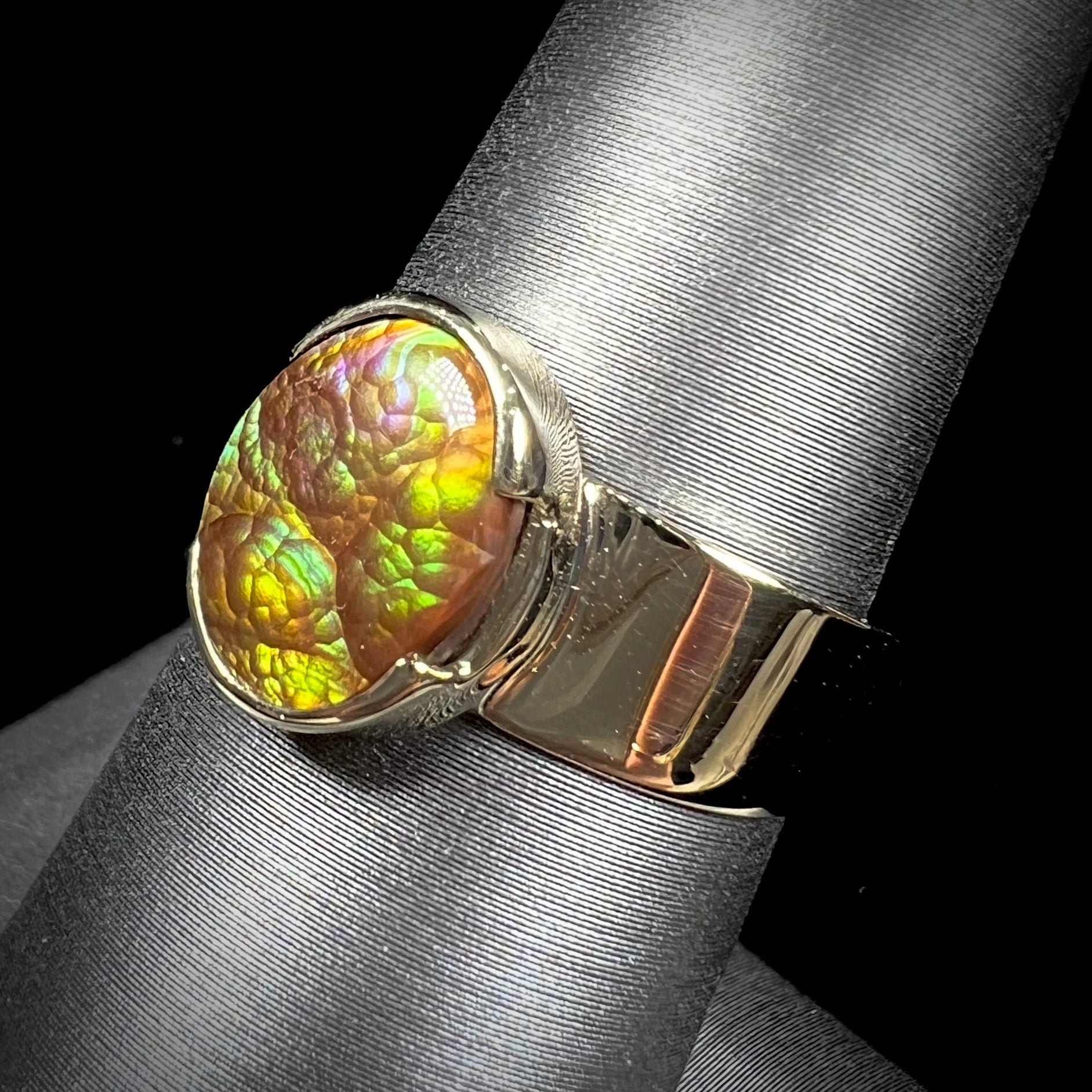 A unisex Mexican fire agate solitaire ring set in yellow gold.  The stone is predominantly green and purple.