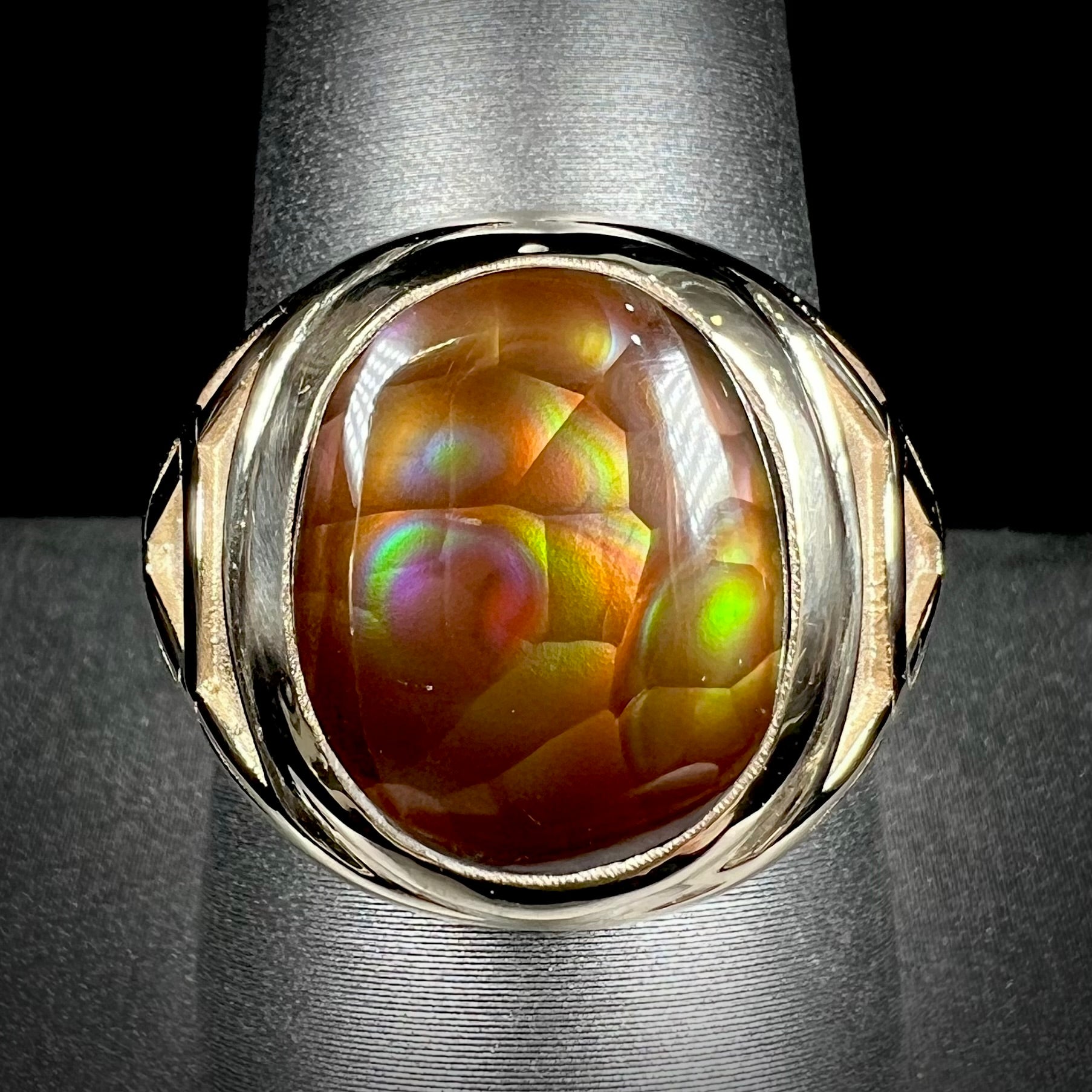 A men's solid yellow gold ring set with a Mexican fire agate stone.  The fire agate has a puple bull's eye pattern.