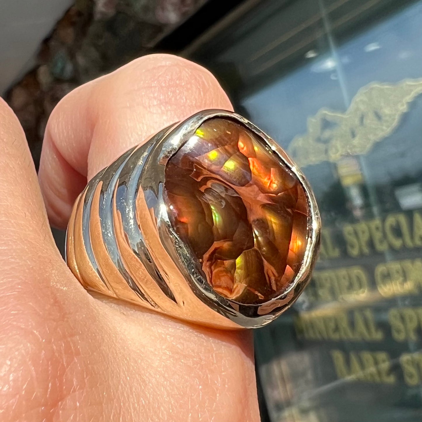 A men's heavy yellow gold ring set with a Mexican fire agate stone and three round brilliant cut diamond accents.