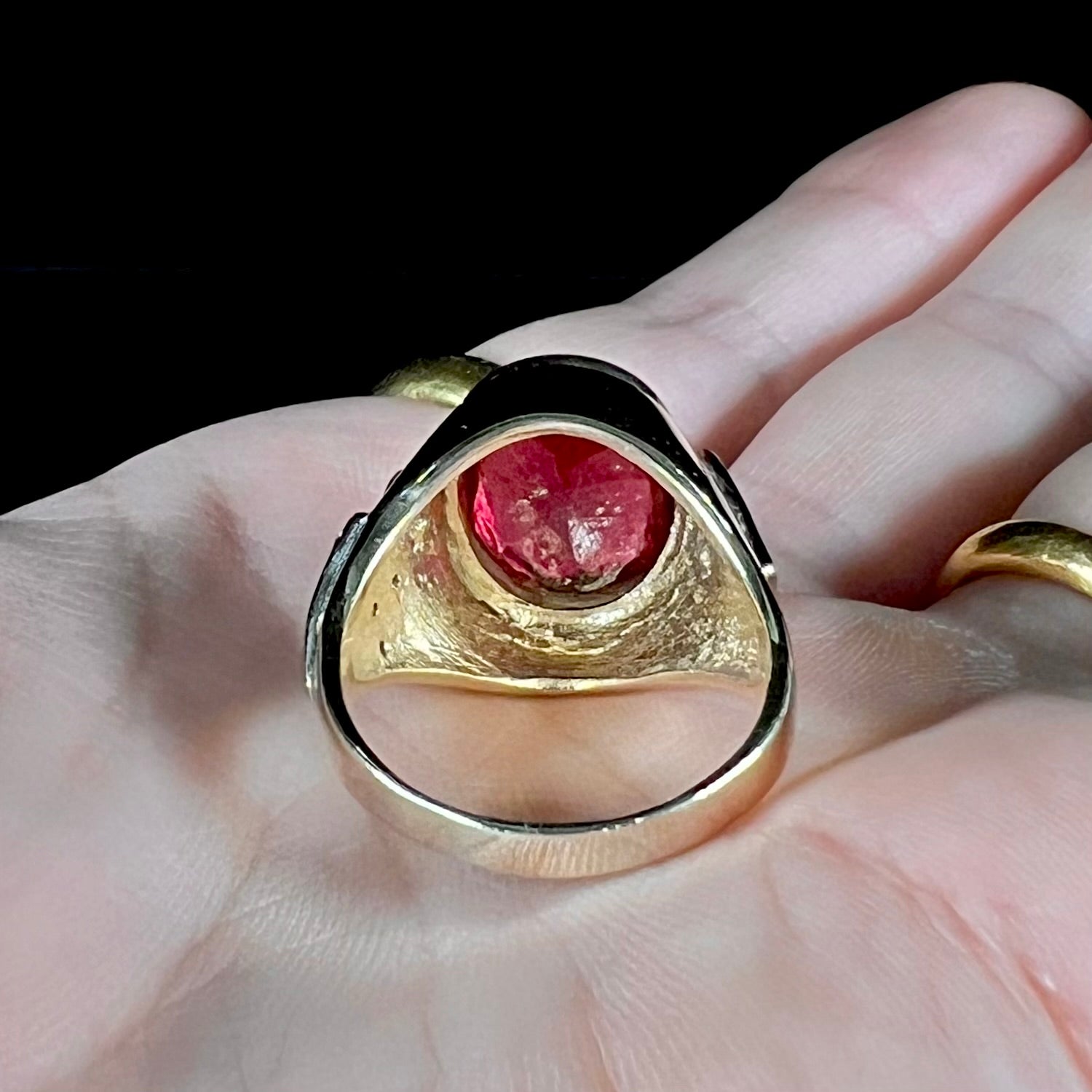 A men's yellow gold ring set with an oval cut rubellite tourmaline with diamond accents.
