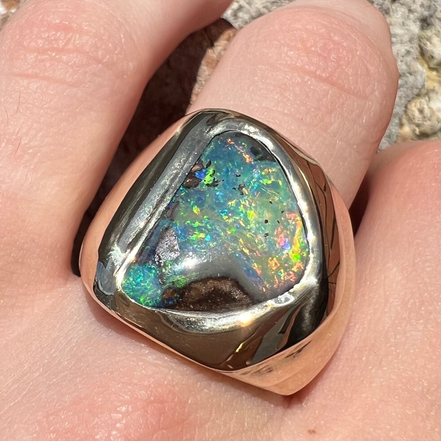 A men's yellow gold solitaire ring set with a triangular shaped natural boulder opal.