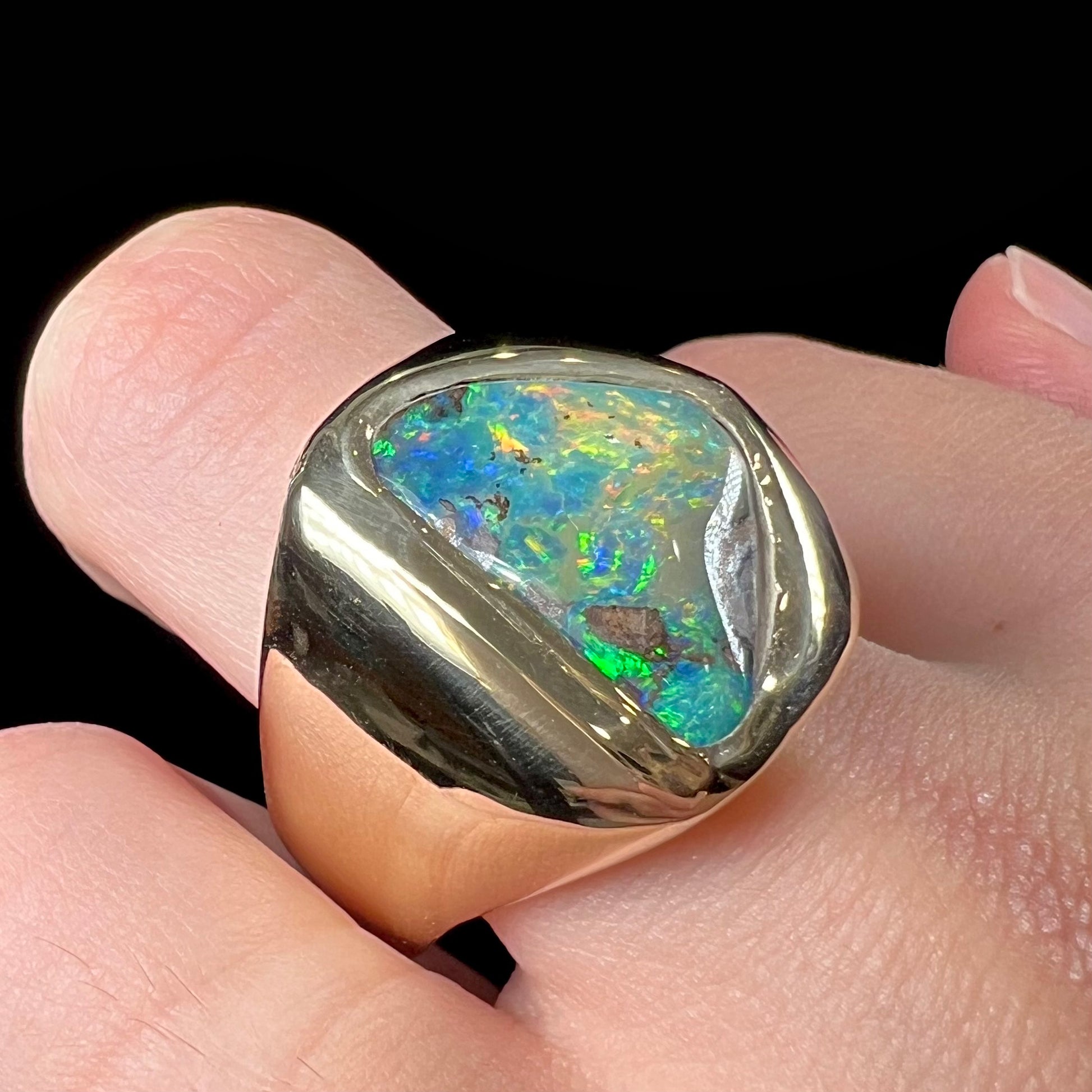 A men's yellow gold solitaire ring set with a triangular shaped natural boulder opal.