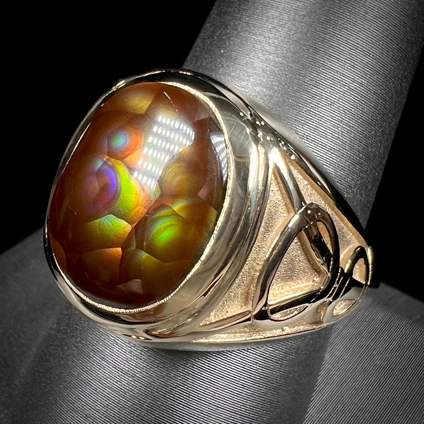 A men's solid yellow gold ring set with a Mexican fire agate stone.  The fire agate has a puple bull's eye pattern.