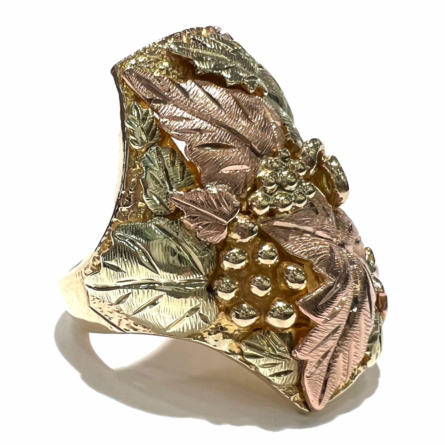 A men's solid gold ring.  The ring is Black Hills gold featuring a grapevine and leaf motif with rose and green gold designs.