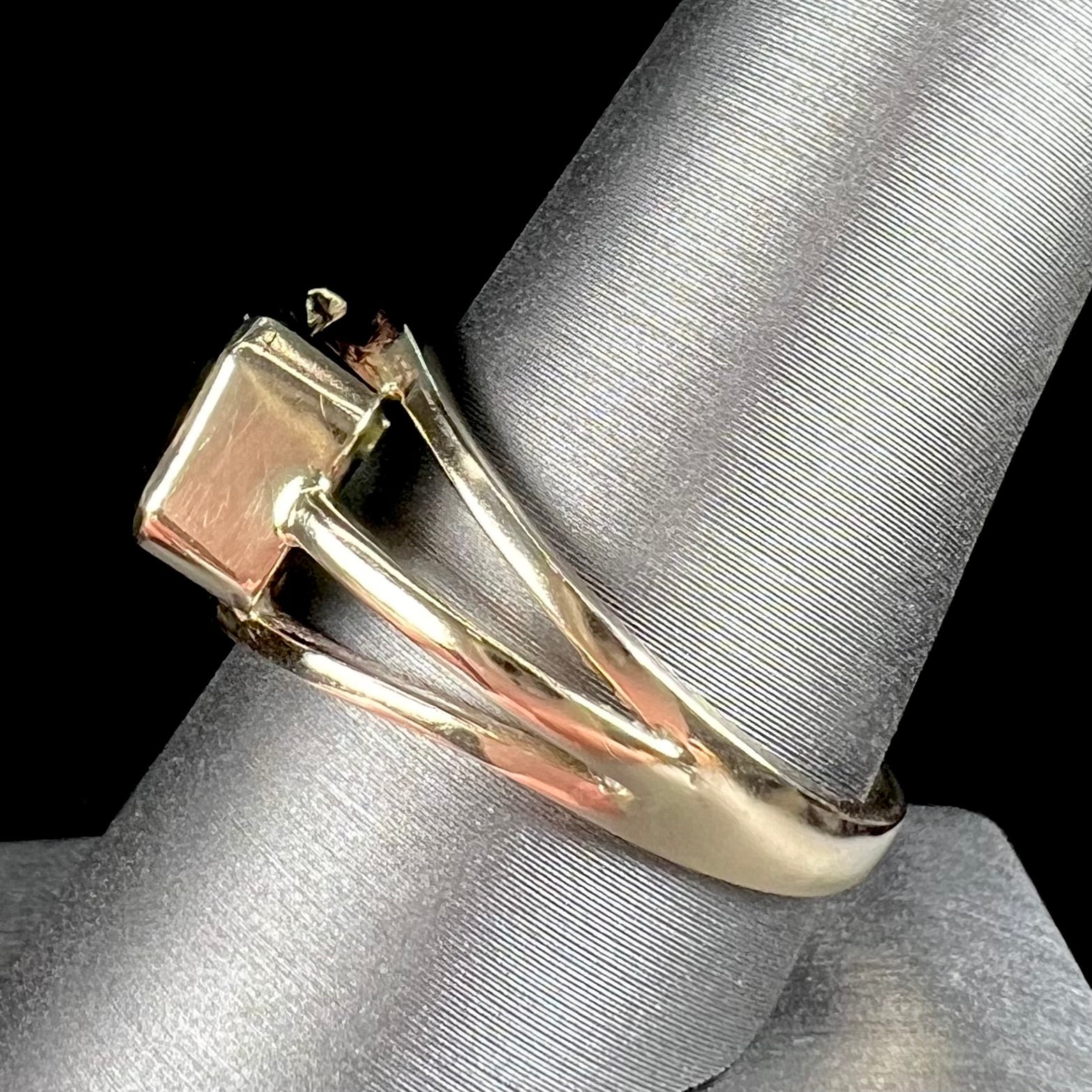 A men's emerald cut tricolor tourmaline solitaire ring in yellow gold.  The tourmaline shifts from green to blue green to blue.